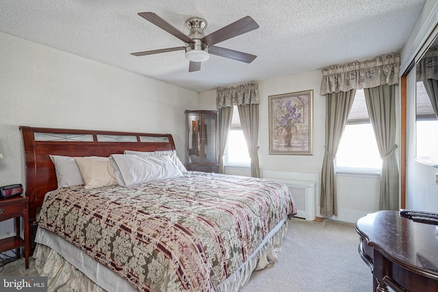 carpeted bedroom featuring ceiling fan and a textured ceiling