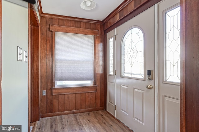 foyer entrance with light hardwood / wood-style flooring and wood walls