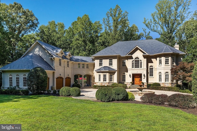 french provincial home with a garage, stucco siding, a chimney, and a front yard