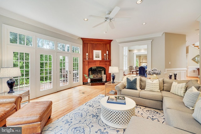 living room featuring crown molding, recessed lighting, a fireplace with raised hearth, a ceiling fan, and wood finished floors