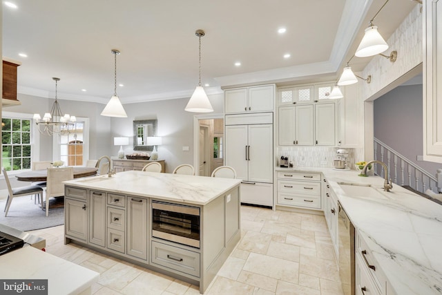 kitchen with built in appliances, sink, light stone countertops, and hanging light fixtures