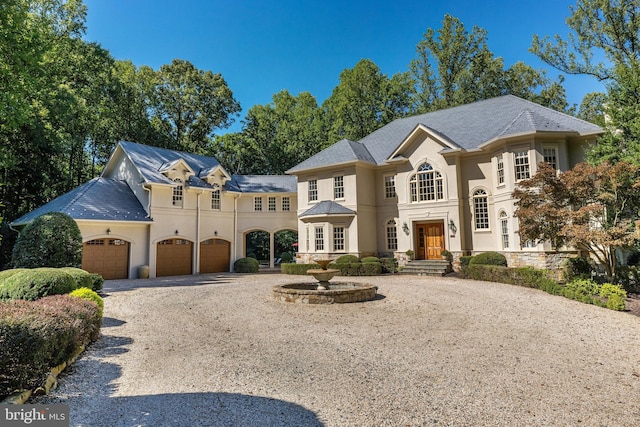 view of front facade with a garage, gravel driveway, and stucco siding