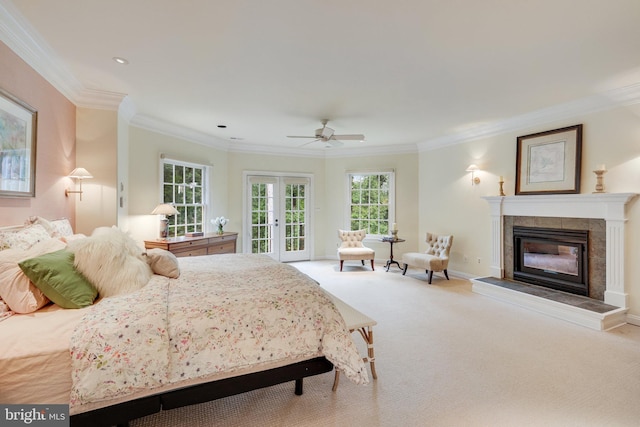 bedroom featuring a tile fireplace, ornamental molding, light colored carpet, access to exterior, and french doors