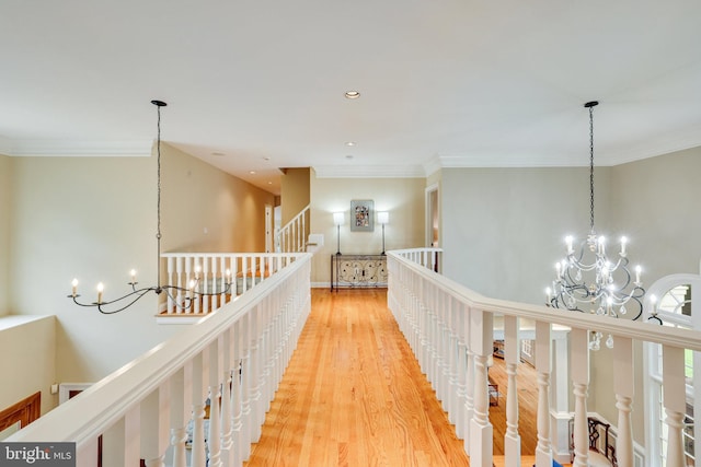 hallway featuring light wood-style flooring, crown molding, an upstairs landing, a chandelier, and recessed lighting