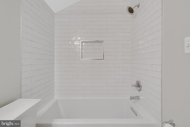 bathroom featuring toilet, vaulted ceiling, and shower / bathing tub combination