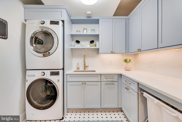 laundry room with stacked washing maching and dryer, a sink, and cabinet space