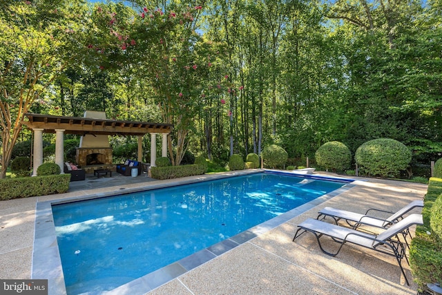 view of swimming pool featuring a patio area, a diving board, and an outdoor stone fireplace