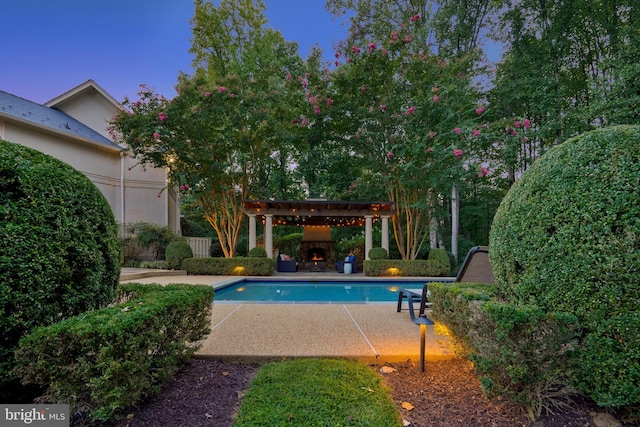 view of swimming pool featuring exterior fireplace and a patio area