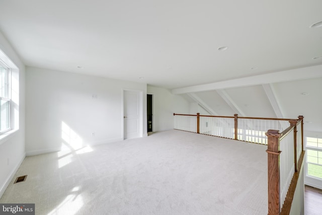 carpeted spare room featuring vaulted ceiling with beams