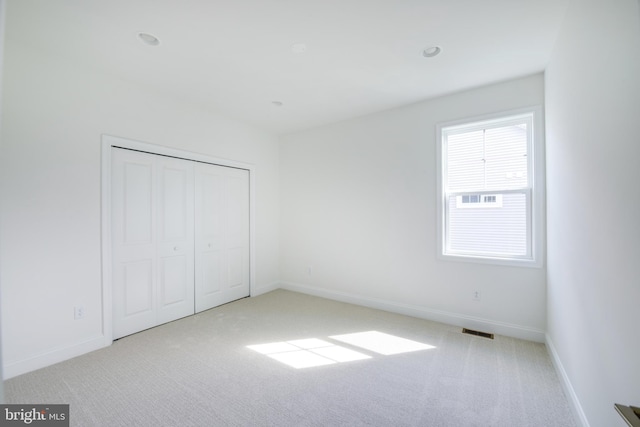 unfurnished bedroom with light carpet and a closet