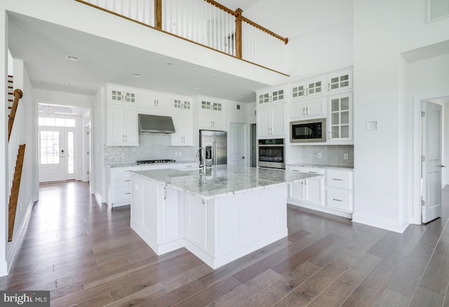 kitchen featuring white cabinetry, wall chimney exhaust hood, and a kitchen island with sink