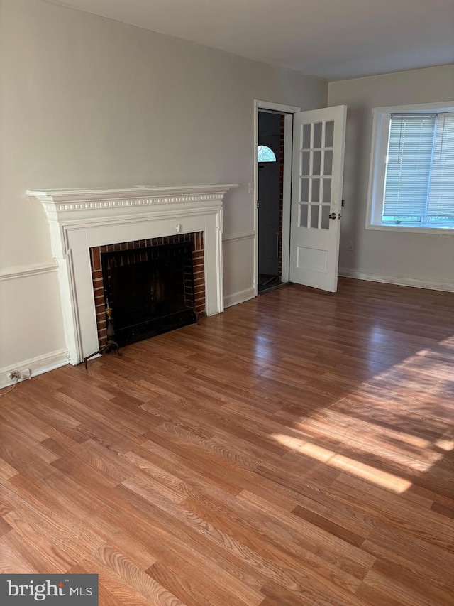 unfurnished living room with a brick fireplace and hardwood / wood-style floors