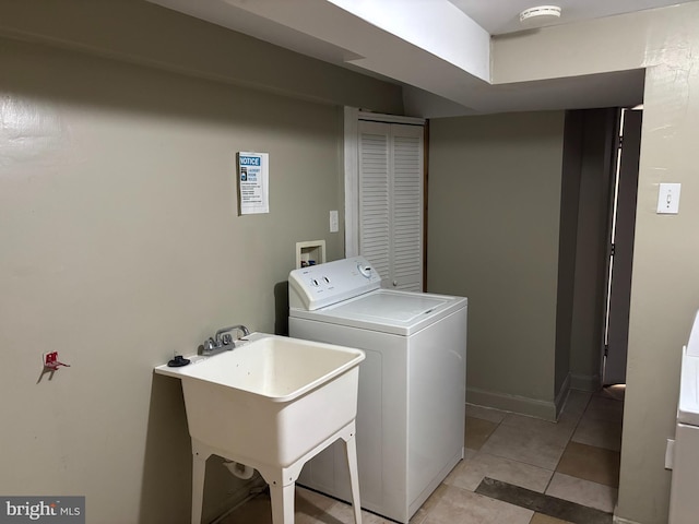 laundry area featuring washing machine and clothes dryer, sink, and light tile patterned floors