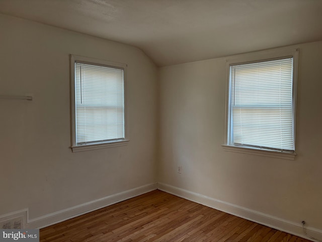 empty room featuring vaulted ceiling and light wood-type flooring