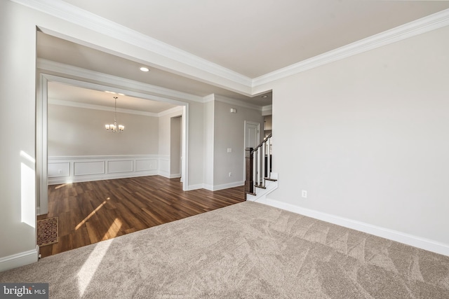 empty room featuring crown molding, a chandelier, and dark colored carpet