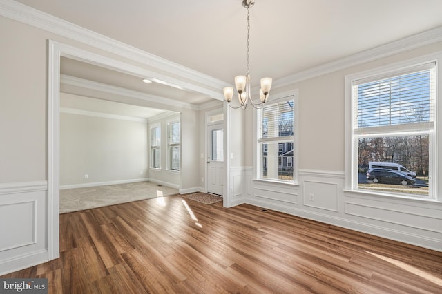 unfurnished dining area with crown molding, hardwood / wood-style floors, and a notable chandelier