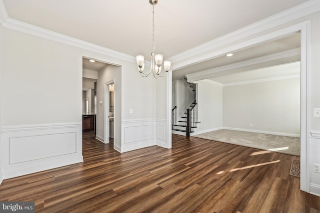 unfurnished dining area with crown molding, dark wood-type flooring, and a notable chandelier