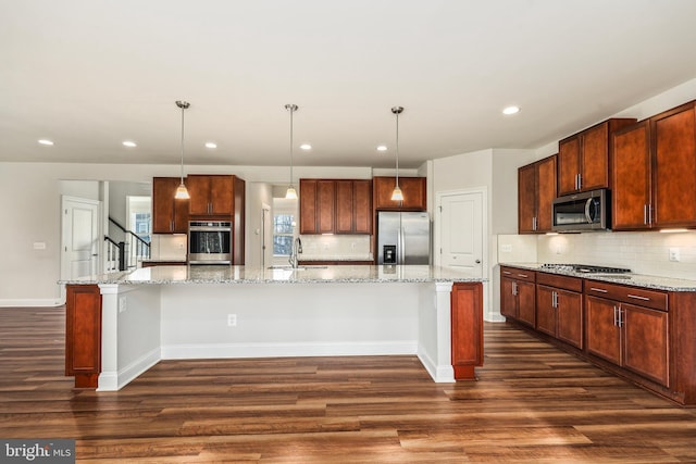 kitchen with sink, appliances with stainless steel finishes, hanging light fixtures, a spacious island, and light stone counters