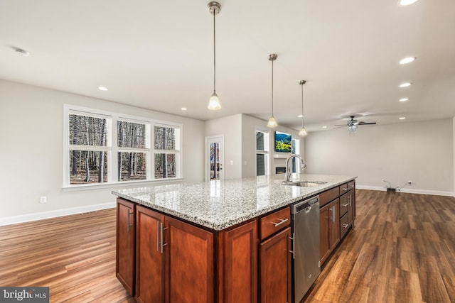 kitchen with sink, dishwasher, a kitchen island with sink, hanging light fixtures, and light stone counters