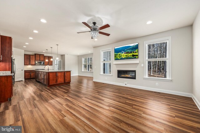 unfurnished living room featuring ceiling fan, sink, and dark hardwood / wood-style flooring