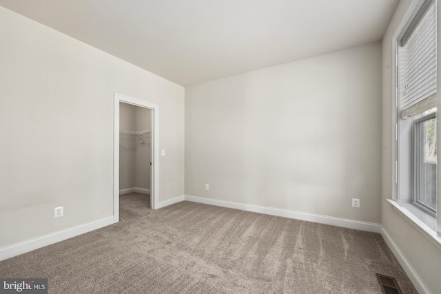 unfurnished bedroom featuring a closet, a spacious closet, and carpet