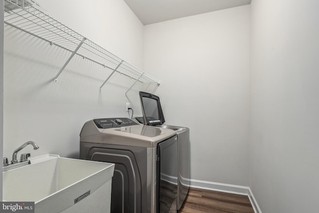 clothes washing area featuring sink, dark wood-type flooring, and washer and clothes dryer