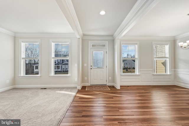 entryway featuring an inviting chandelier, crown molding, and plenty of natural light