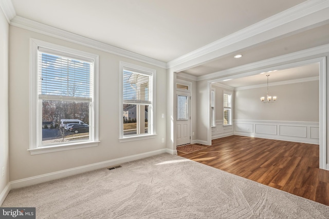 carpeted empty room featuring ornamental molding and a chandelier