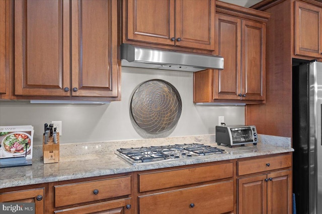 kitchen with appliances with stainless steel finishes, brown cabinets, and under cabinet range hood