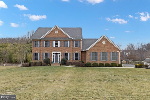 view of front facade featuring fence, a front lawn, and brick siding