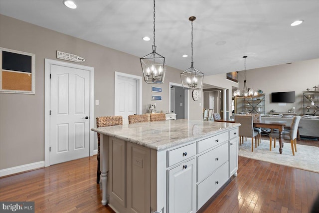 kitchen featuring dark wood-style floors, open floor plan, white cabinets, and light stone countertops