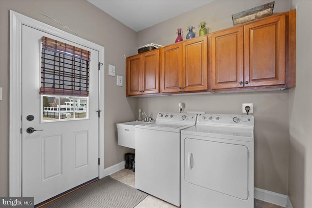 laundry room with cabinet space, light tile patterned floors, baseboards, washing machine and dryer, and a sink