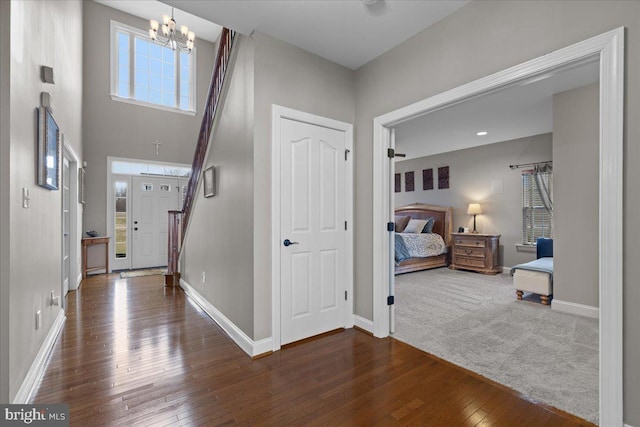 foyer featuring wood-type flooring, stairs, a chandelier, and baseboards