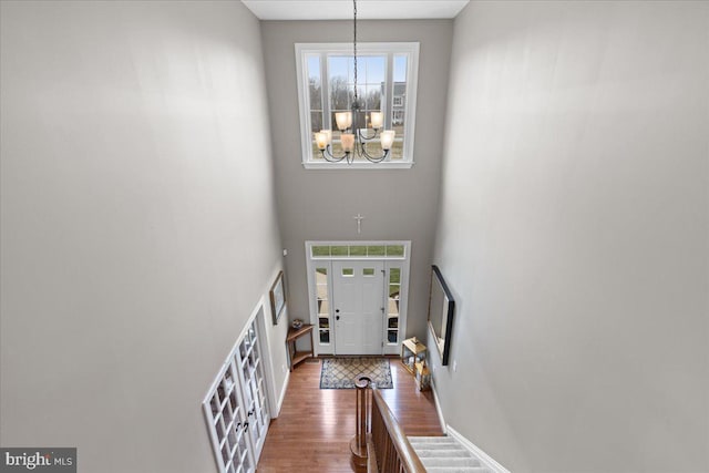 entrance foyer featuring a wealth of natural light, wood finished floors, a towering ceiling, and an inviting chandelier