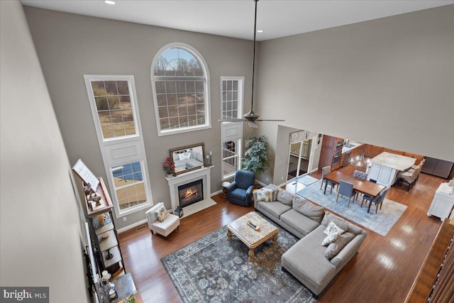 living area featuring ceiling fan, recessed lighting, a fireplace, wood finished floors, and baseboards