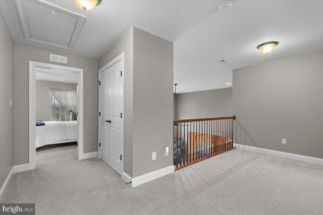 corridor with baseboards, carpet flooring, visible vents, and attic access