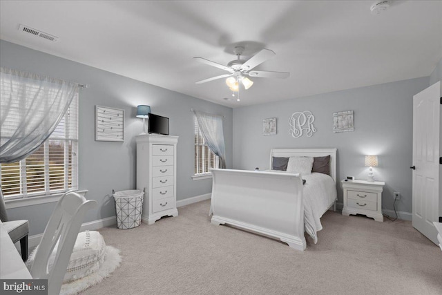 carpeted bedroom featuring a ceiling fan, visible vents, baseboards, and multiple windows