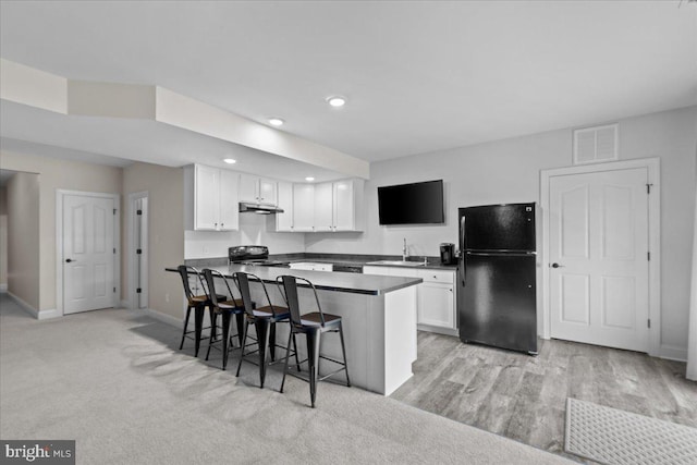 kitchen with visible vents, dark countertops, black appliances, white cabinetry, and a sink