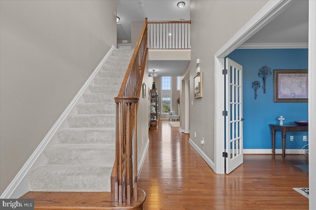 entryway featuring ornamental molding, stairway, baseboards, and wood finished floors