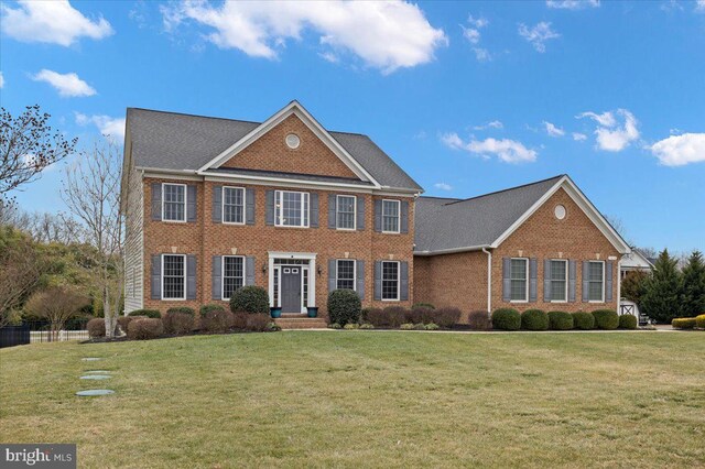 colonial inspired home featuring brick siding and a front yard