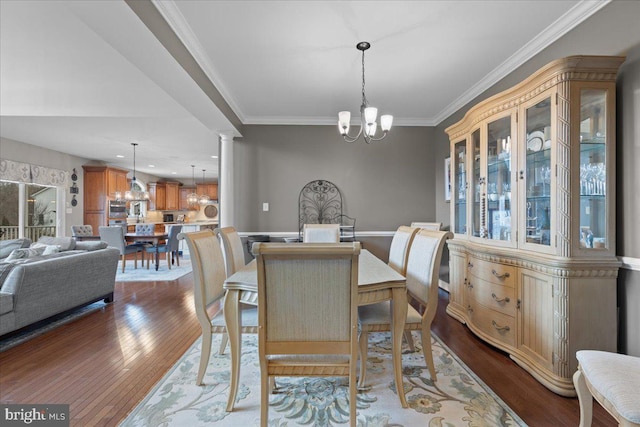 dining space featuring ornate columns, crown molding, dark wood finished floors, and an inviting chandelier