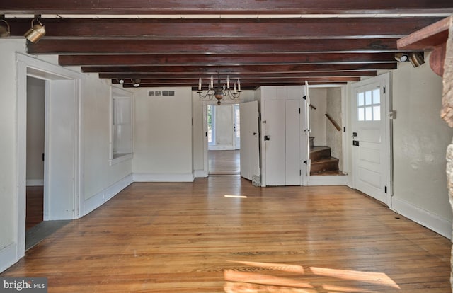 interior space with an inviting chandelier, wood-type flooring, and beam ceiling