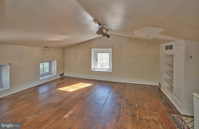 additional living space featuring dark wood-type flooring and vaulted ceiling