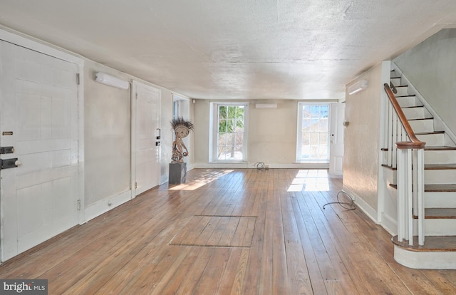 foyer with an AC wall unit, hardwood / wood-style floors, and a textured ceiling