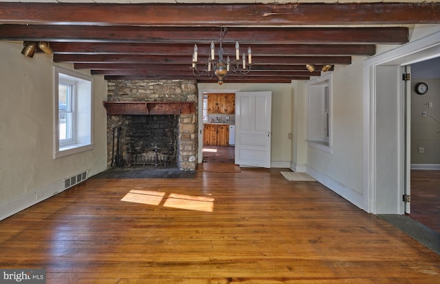 unfurnished living room with beam ceiling, hardwood / wood-style floors, a notable chandelier, and a fireplace