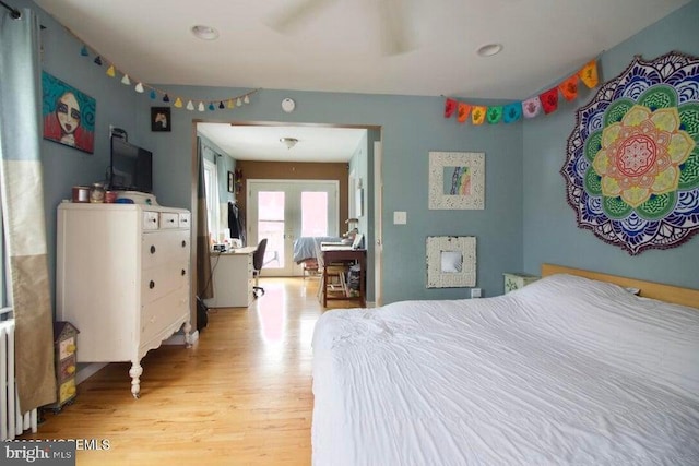 bedroom featuring radiator, french doors, and light wood-type flooring