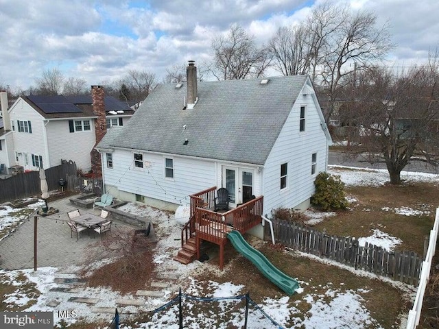 snow covered property with french doors and a playground