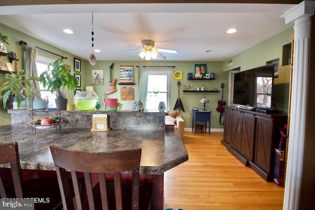 dining space with ornate columns, ceiling fan, and light hardwood / wood-style floors