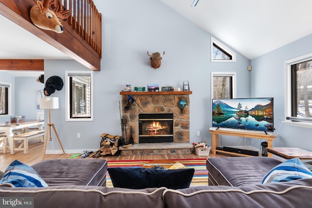 living room featuring wood-type flooring, high vaulted ceiling, a wealth of natural light, and a fireplace