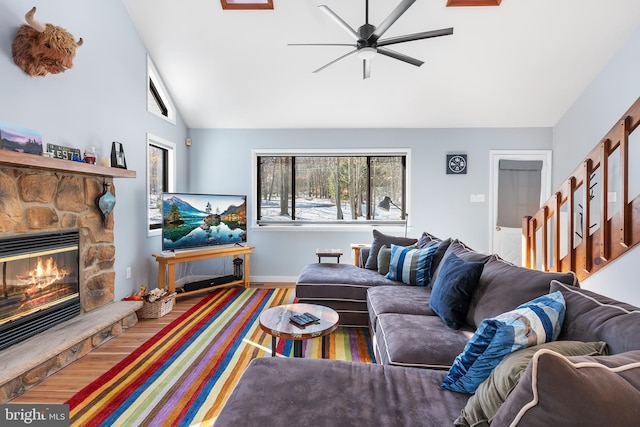 living room featuring vaulted ceiling, hardwood / wood-style floors, ceiling fan, and a fireplace